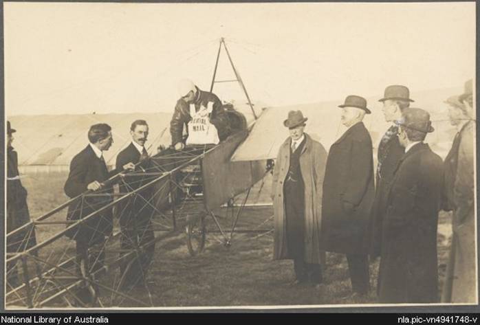 Darge, Algernon, 1878-1941. Maurice Guillaux in his Bleriot XI monoplane holding aerial mail bag at the Agricultural Society's show grounds before flying to Sydney on first air mail delivery, Melbourne, 16 July 1914 [picture]
