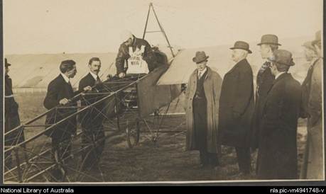 Darge, Algernon, 1878-1941. Maurice Guillaux in his Bleriot XI monoplane holding aerial mail bag at the Agricultural Society's show grounds before flying to Sydney on first air mail delivery, Melbourne, 16 July 1914 [picture]