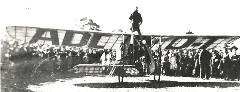  First flight from Melbourne to Sydney showing pilot Maurice Guillaux standing on a Bleriot monoplane with a 50 horsepower Gnome engine, Wangaratta, July 1914 [picture].